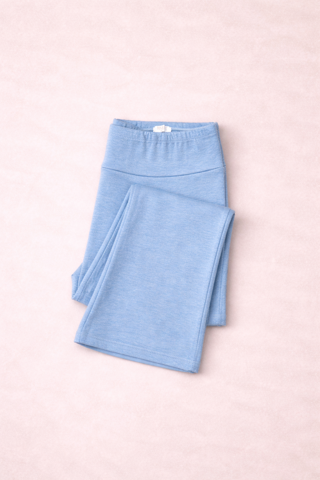 Folded light blue leggings on a pink background