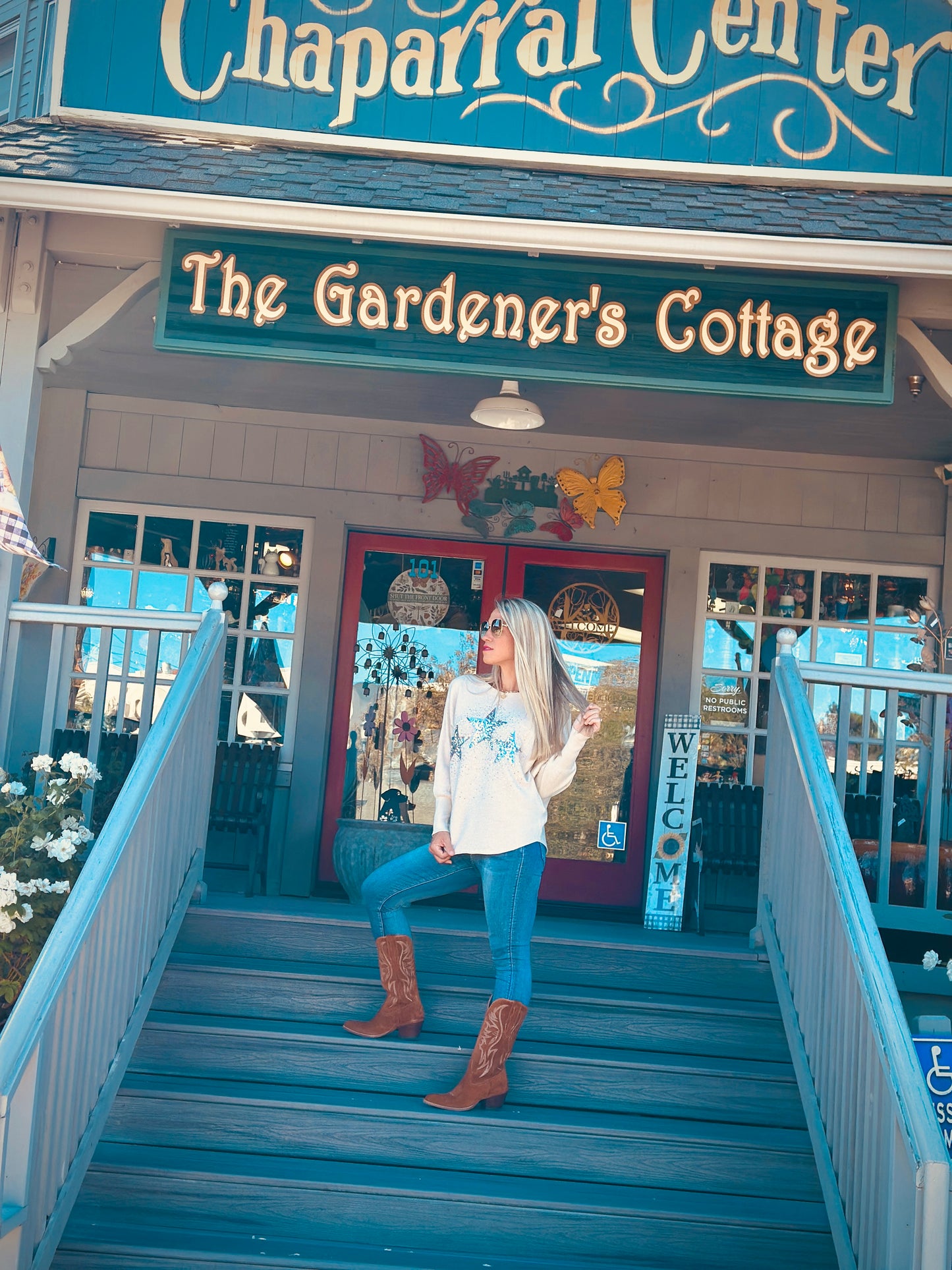 Woman standing on blue steps in front of 'The Gardener's Cottage' building
