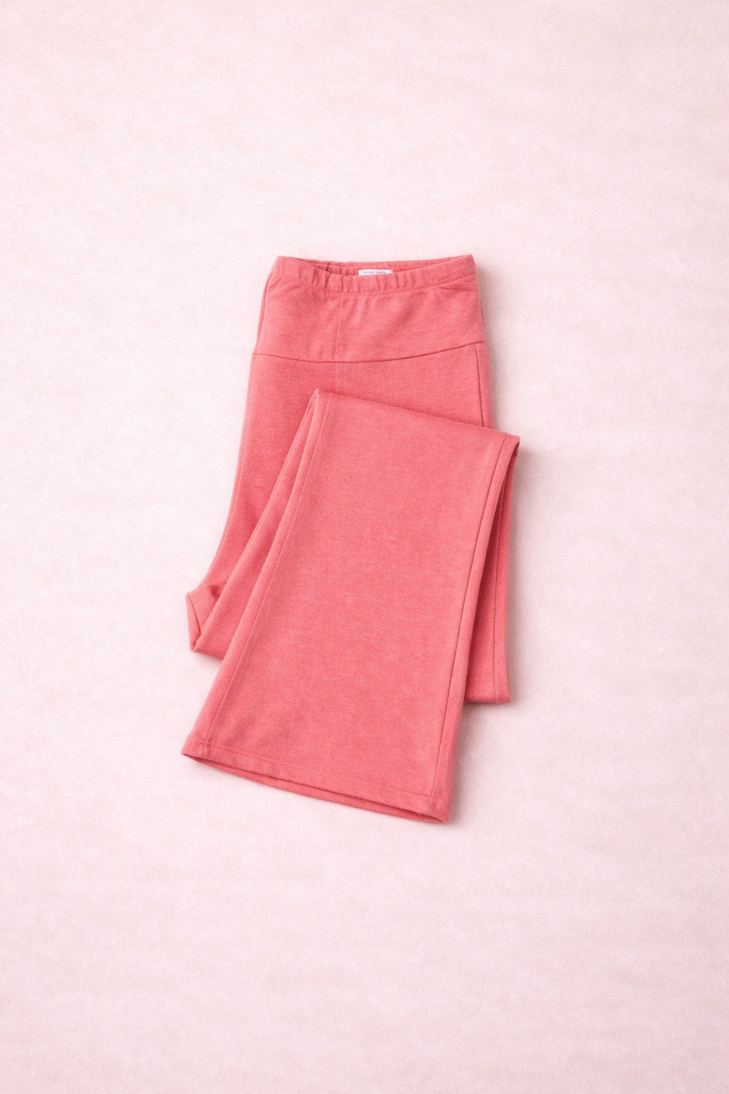 Folded coral leggings on a pink background