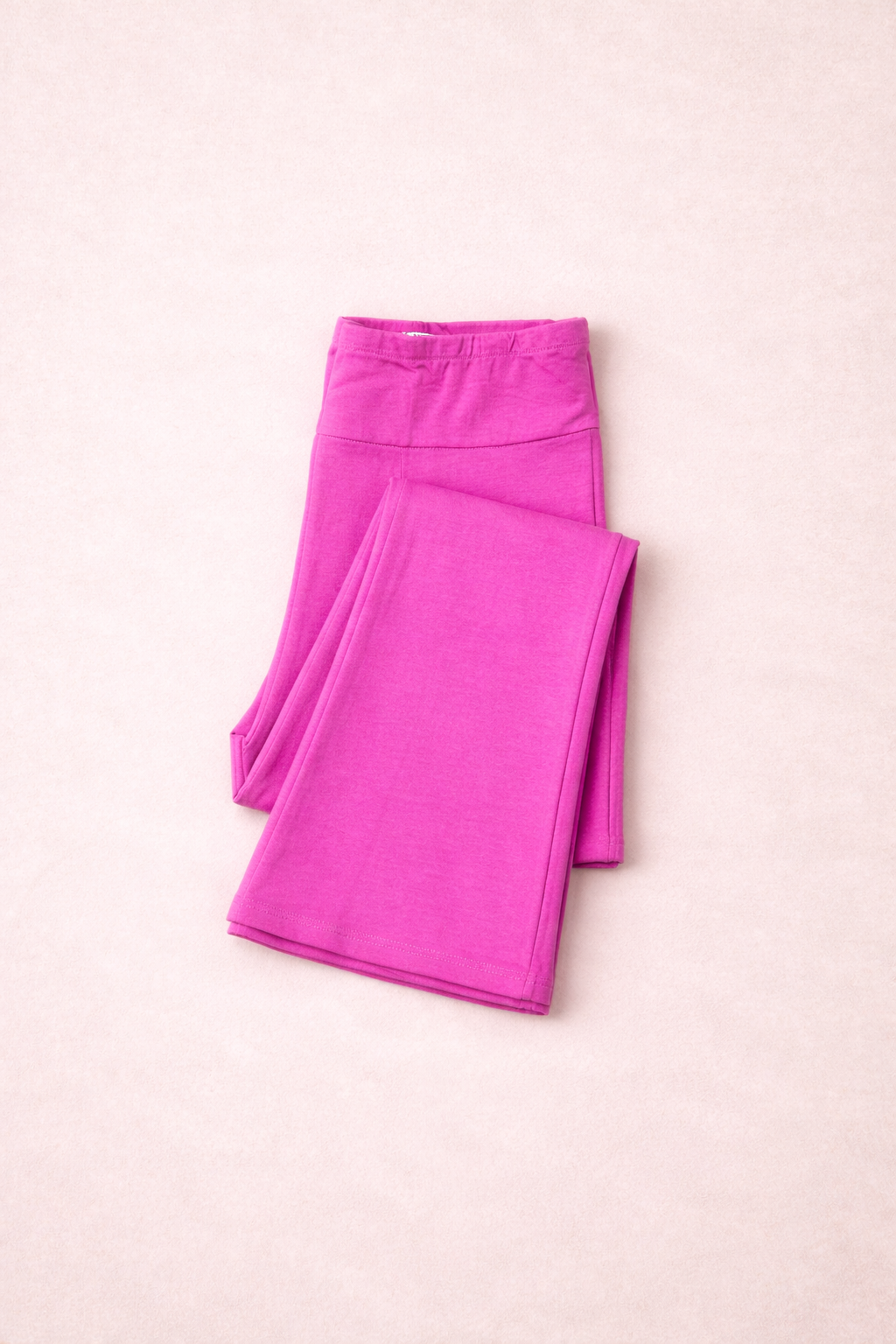 Folded pink leggings on a pink background
