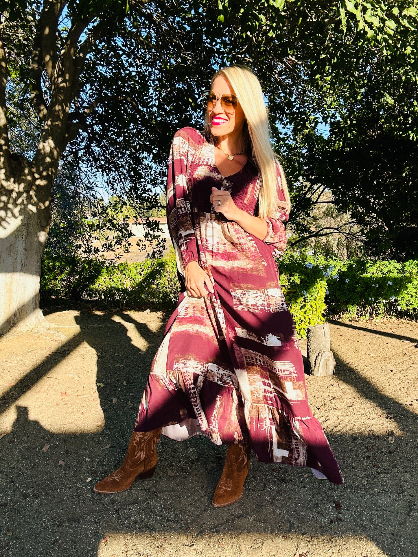 Woman in a patterned dress standing outdoors with trees in the background