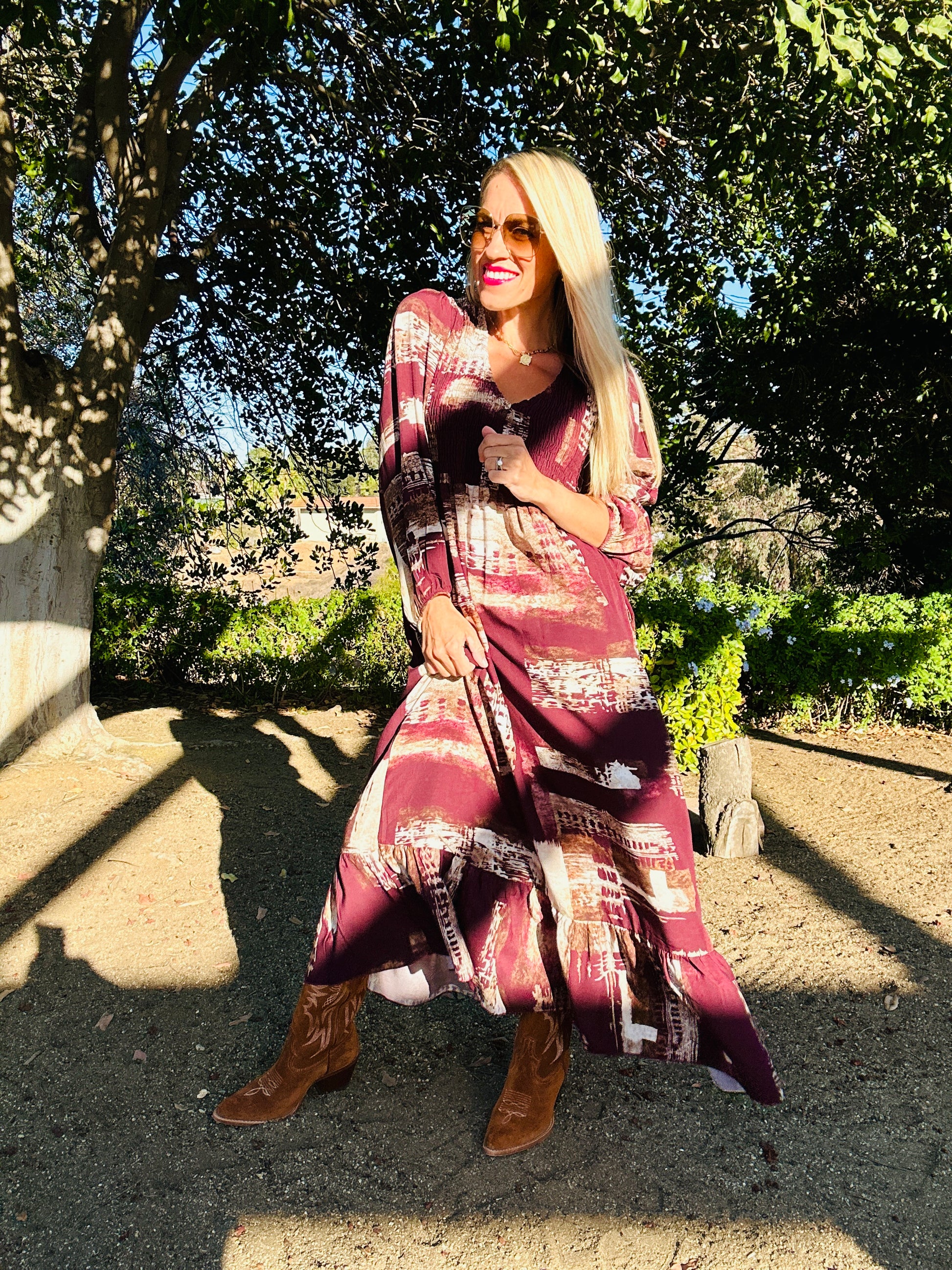 Woman in a patterned dress standing outdoors with trees in the background
