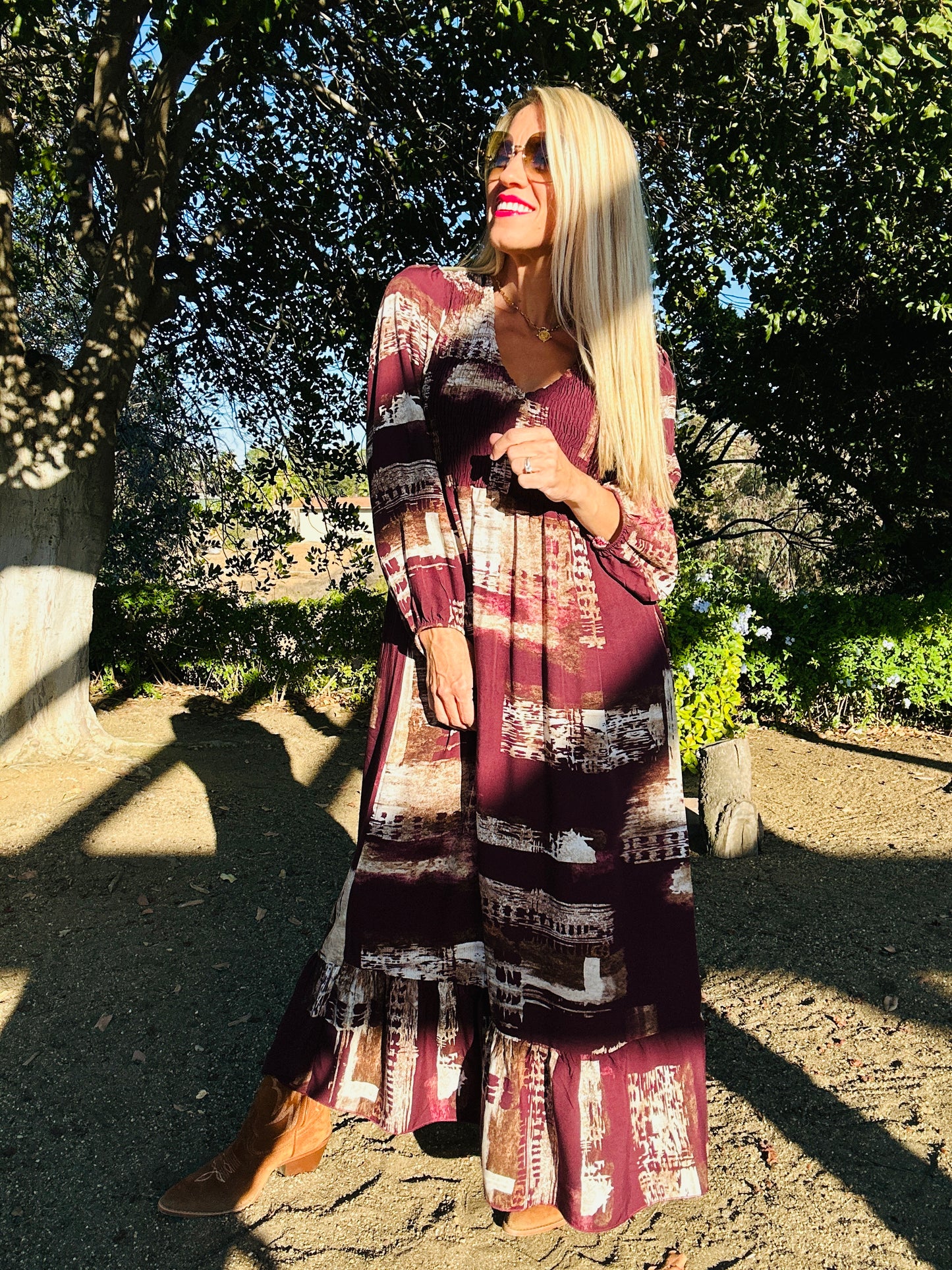 Woman wearing a patterned dress standing outdoors with trees in the background