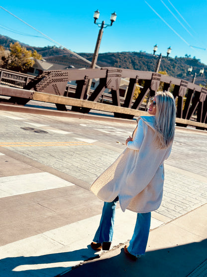 Person standing on a sidewalk with a bridge and scenic background