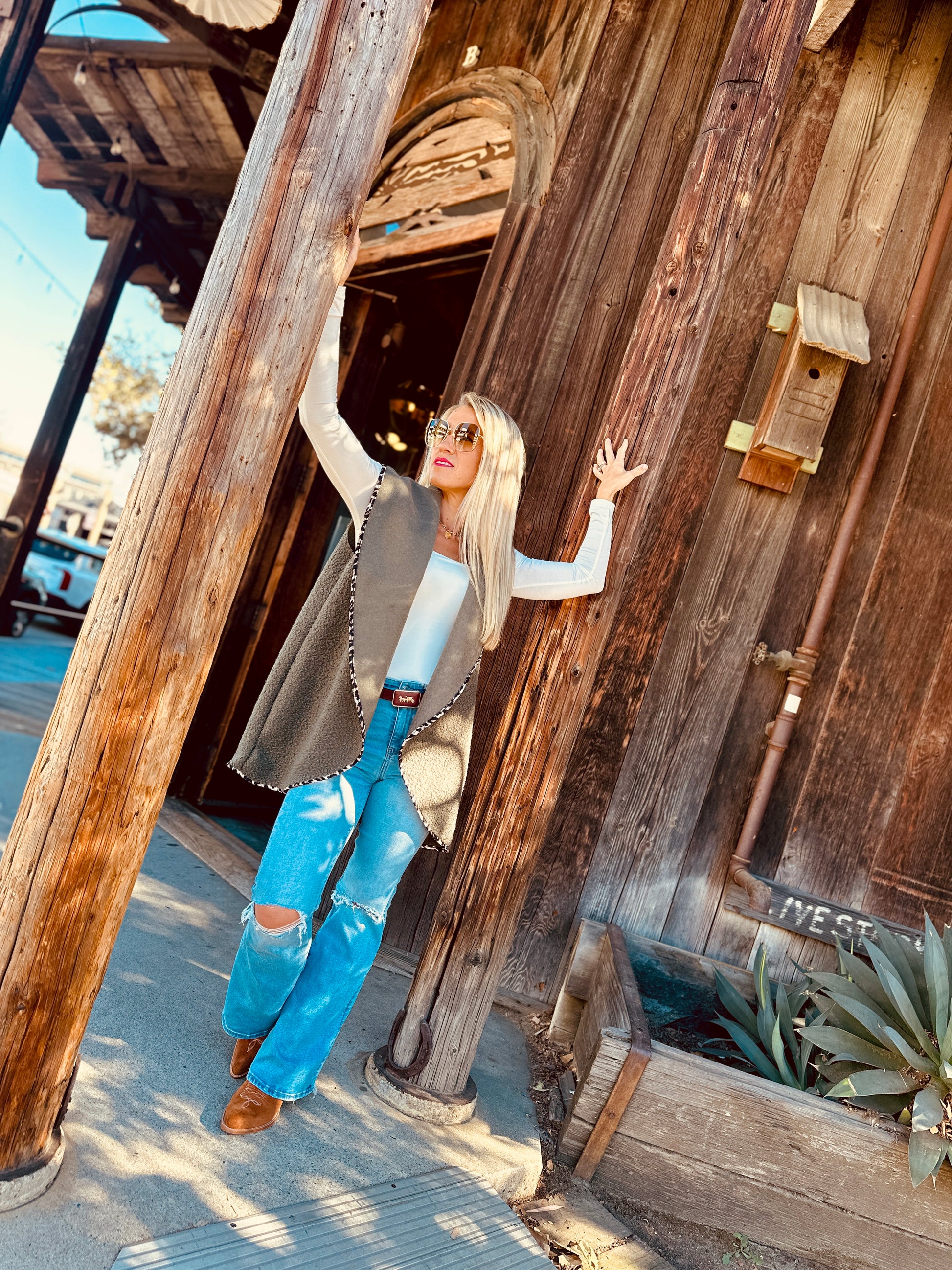 Woman posing in front of a rustic wooden building