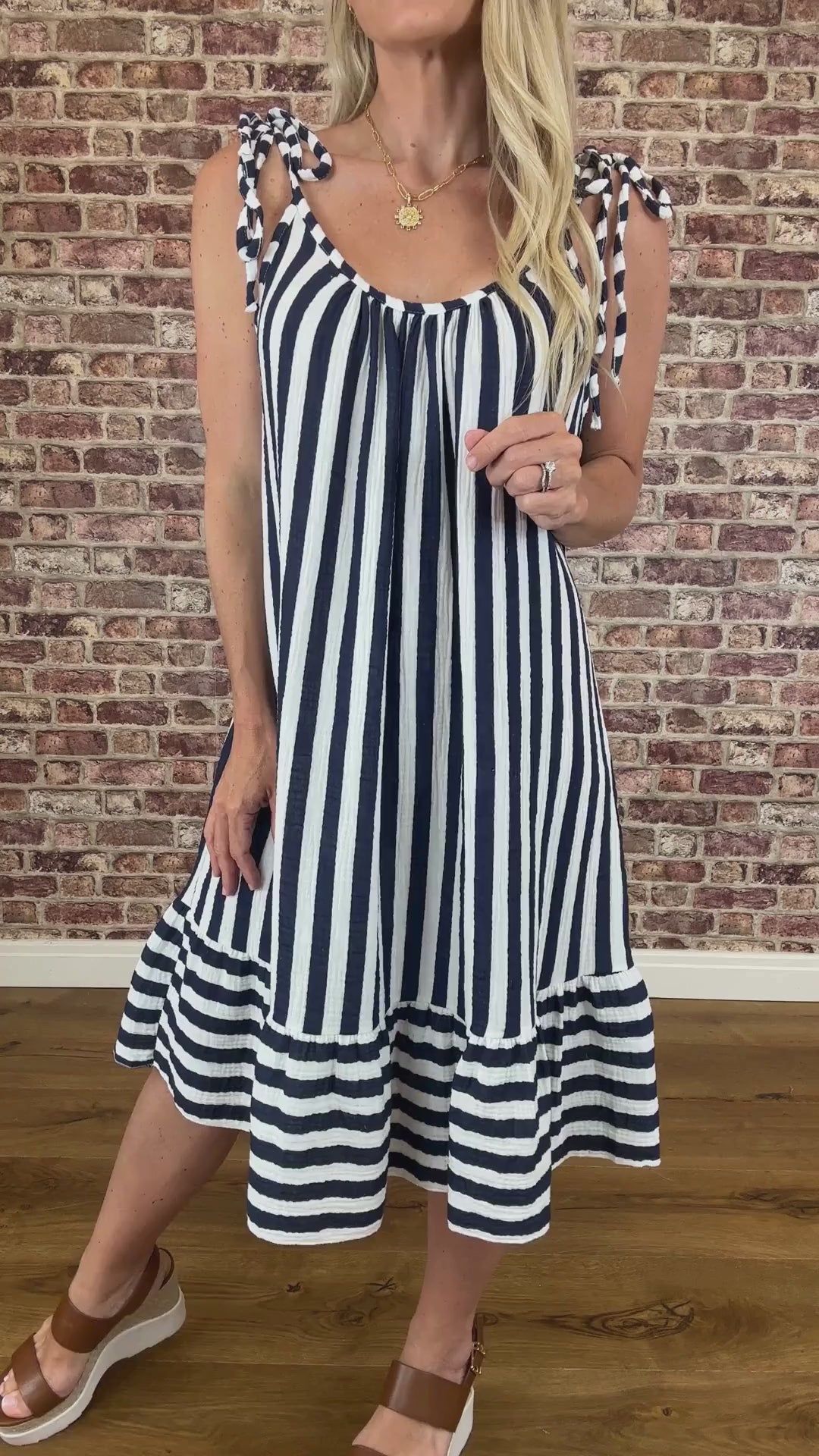 Person wearing a navy and white striped dress against a brick wall.