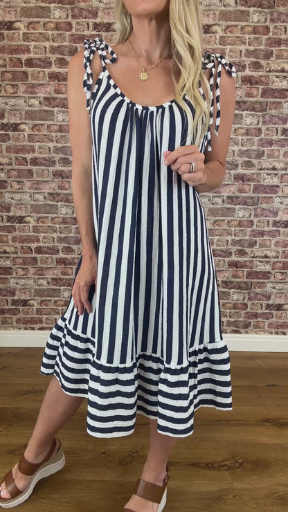 Person wearing a navy and white striped dress against a brick wall.