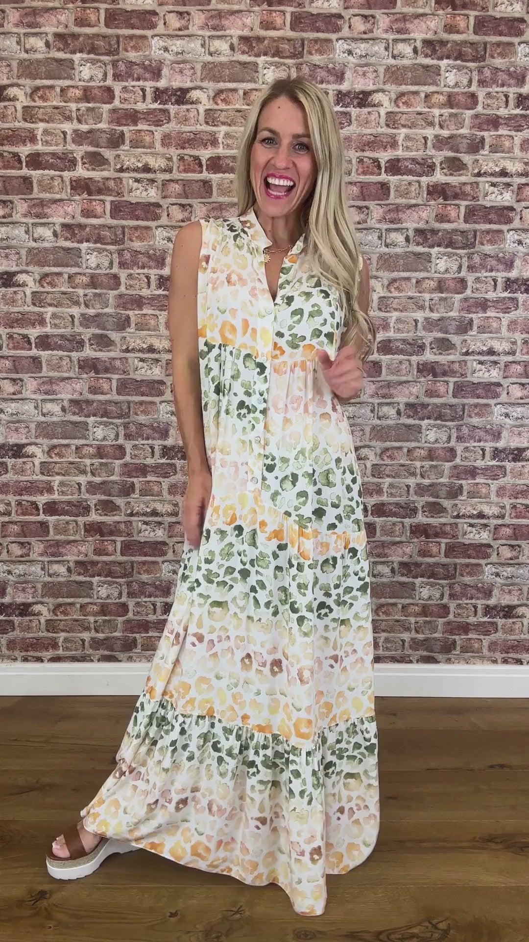 Woman wearing a leopard dress standing against a brick wall.